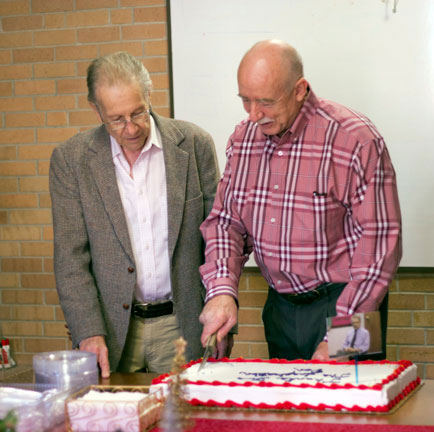 Hufford looks on as Associate Dean and Associate Professor of Education Steve Dunn, Ed.D. cuts a cake at Hufford's retirement party.