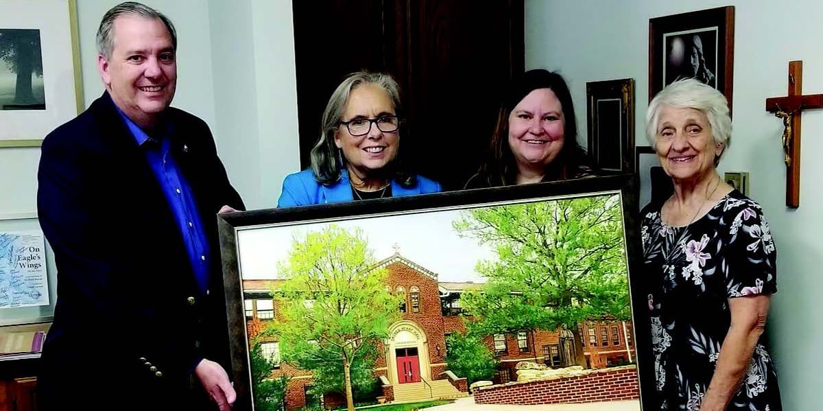 Michelle Garvert displays her painting of Sacred Heart Hall