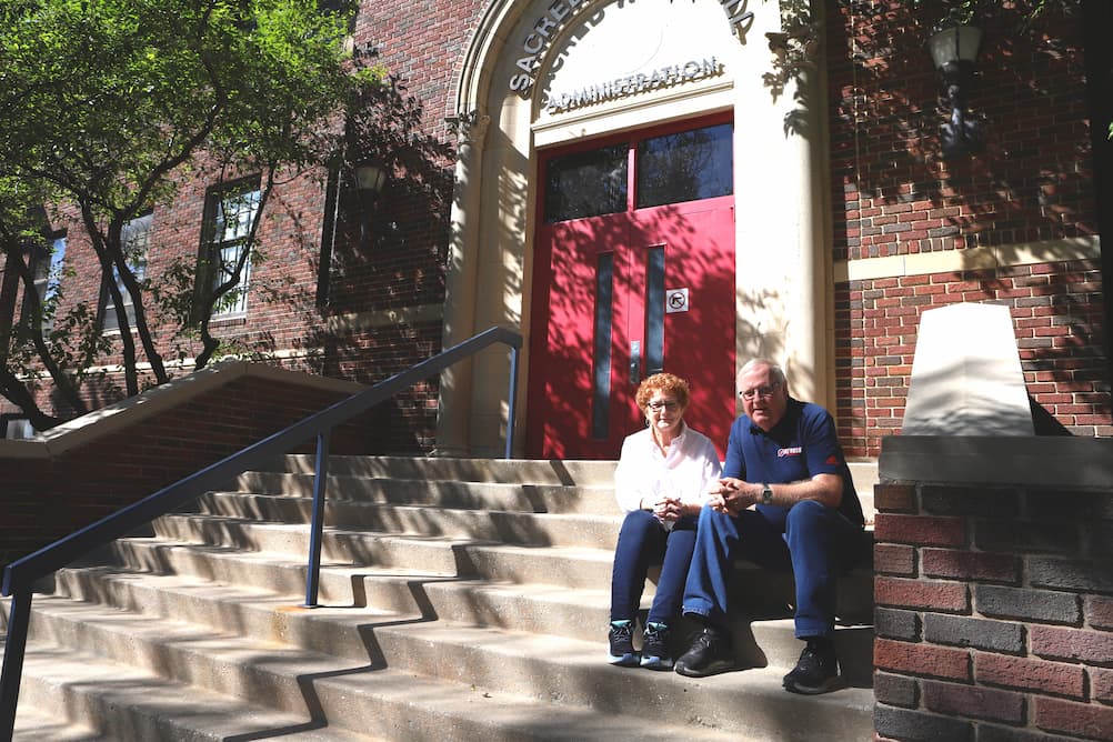 Kirk and Maribeth Lester sit on the steps of Sacred Heart Hall.