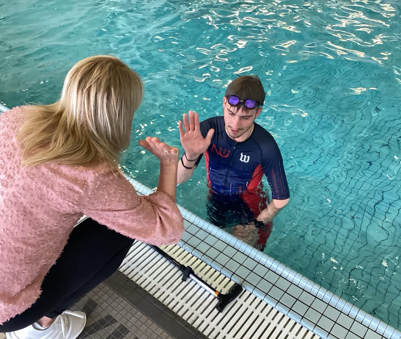 Wagner is high-fived after a successful 200-yard swim at the Newton YMCA, marking his graduation from therapy following his accident.