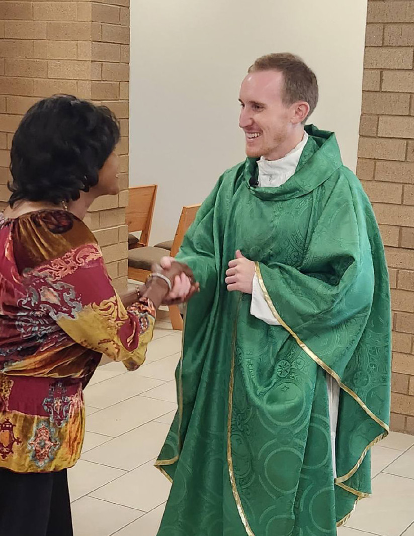 Father Adam Grelinger greets a parishioner following Mass at Holy Savior Catholic Church.