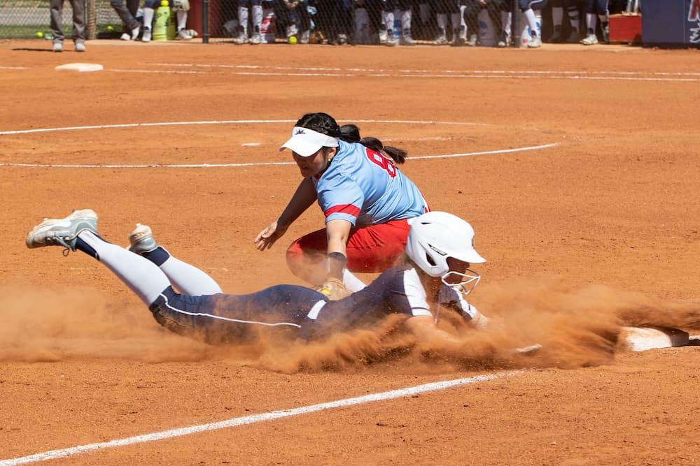 A Newman softball player tags out a member of the opposite team during a slide to first base.