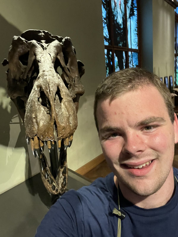 Joseph Luebbe standing next to a dinosaur skull.